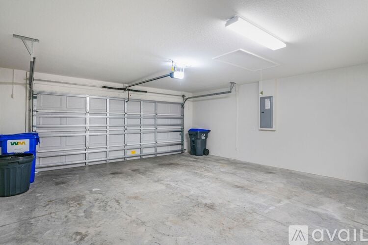 A spacious garage with a closed white door and a blue bin on the floor.