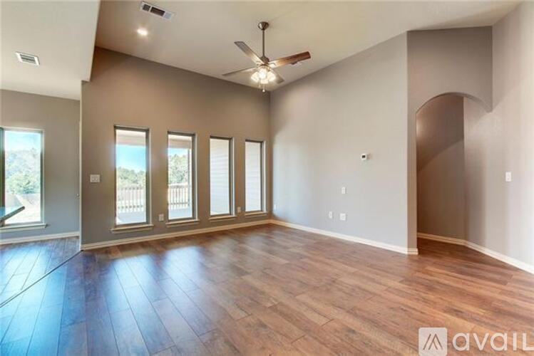 A spacious room with wood flooring and a ceiling fan.