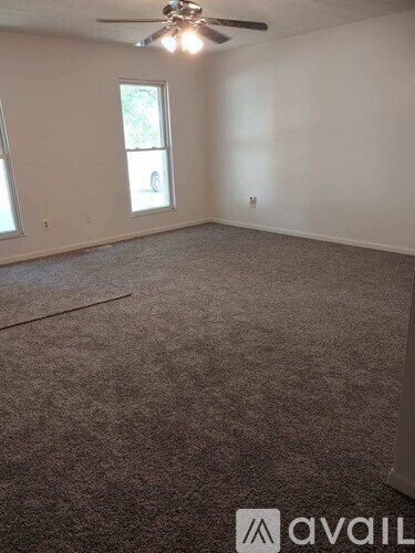 A room with a carpeted floor and a ceiling fan.