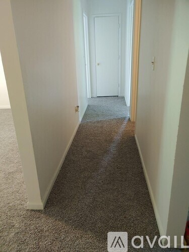 A hallway with a carpeted floor and white walls.