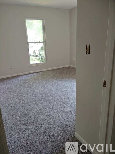 A car is visible through the window of a room with a carpeted floor.