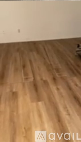 A room with wooden flooring and a wall in the background.