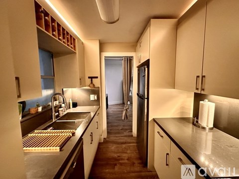 A modern kitchen with a sink, refrigerator, and cabinets.
