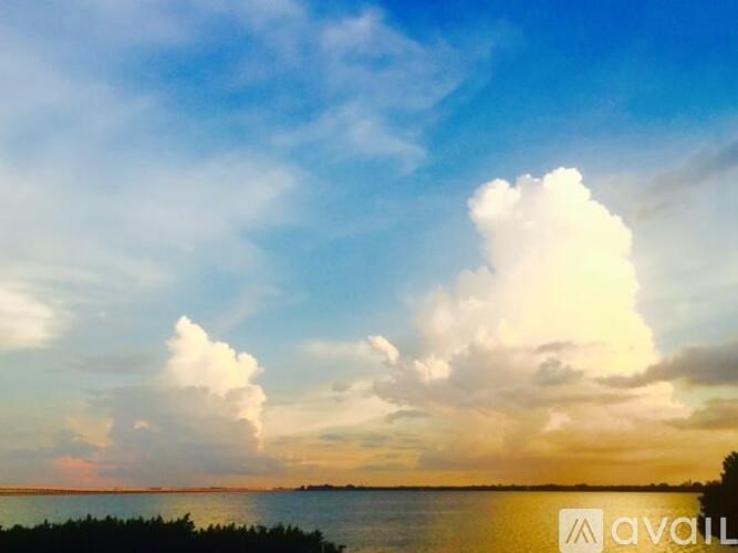 A large cloud is in the sky above a body of water.
