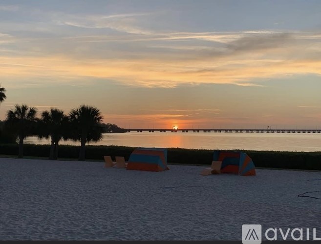 A beach scene with a sunset and beach chairs.