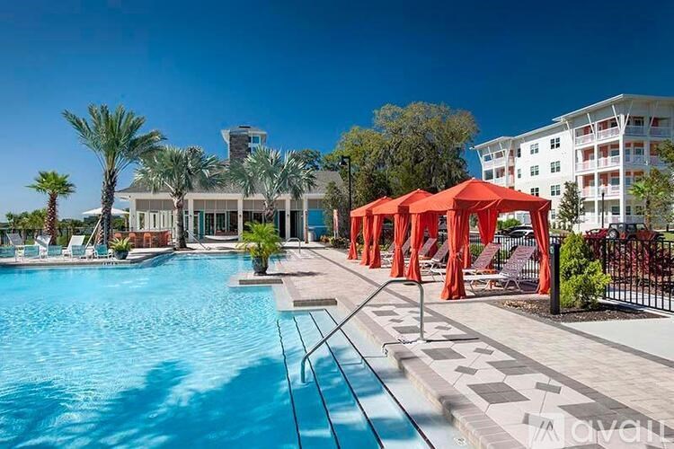 A pool area with a red canopy and a building in the background.