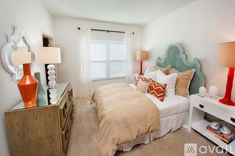 A bedroom with a bed, nightstand, and a dresser with a mirror.