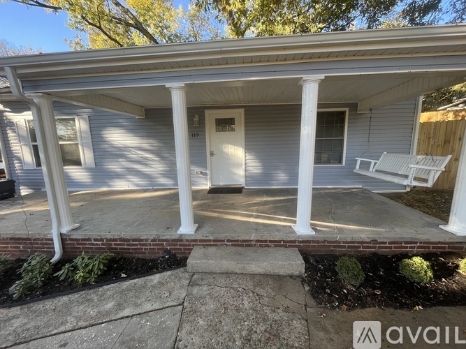 A porch with a white door and pillars.