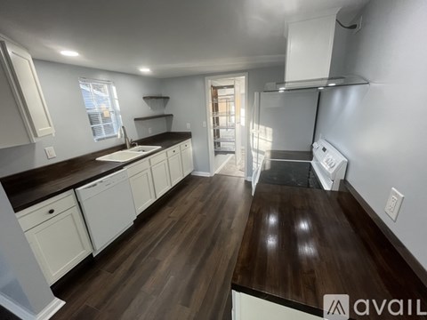 A kitchen with white cabinets and a wooden floor.