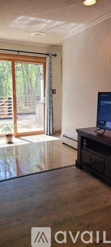 A room with a desk and a window with a view of trees.