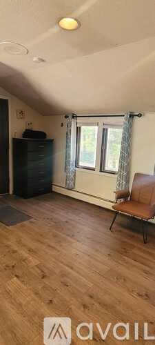 A room with wooden flooring and a window with curtains.