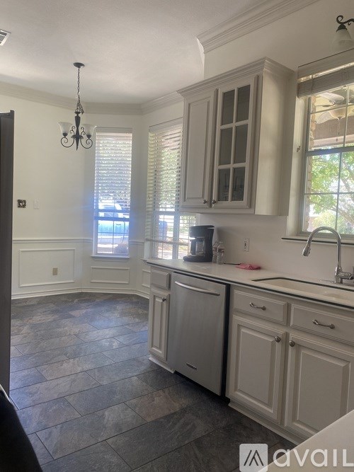 A kitchen with a stone floor and white cabinets.