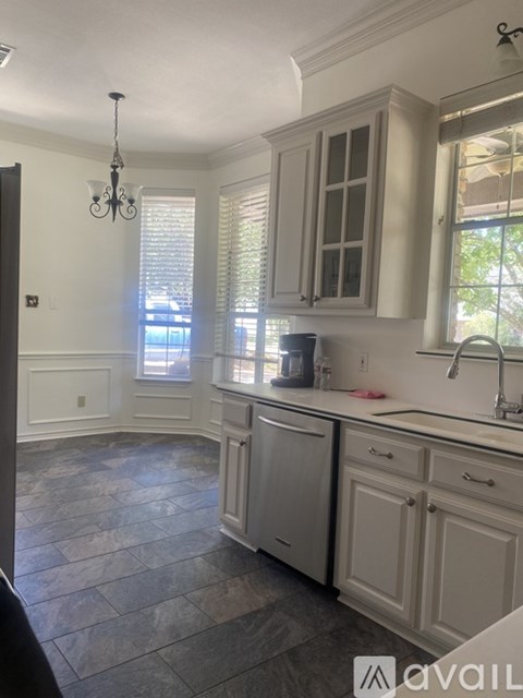 A kitchen with a stone floor and white cabinets.