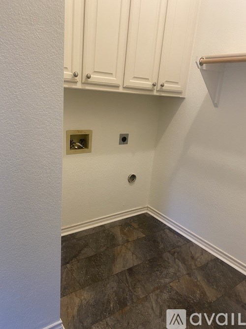 A corner of a room with a tile floor and white cabinets.
