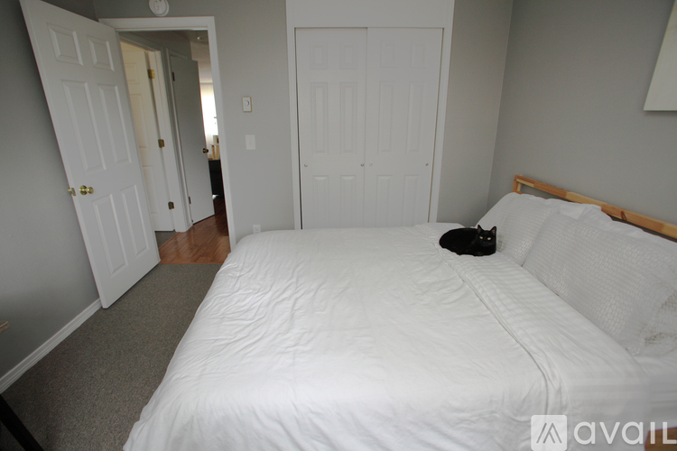 A bedroom with a white bed and a black hat on the bed.
