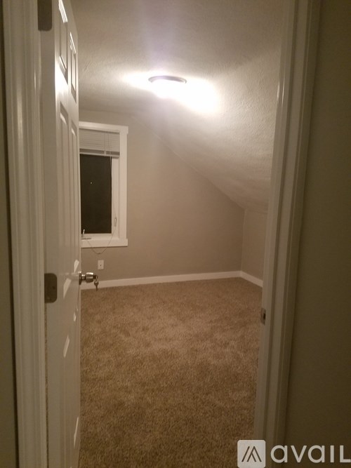 A room with a carpeted floor and a door leading to a window.