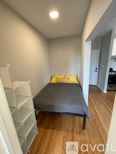 A bedroom with a bed, a shelf, and a wooden floor.