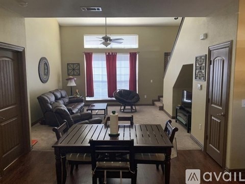 A living room with a brown table and brown chairs.