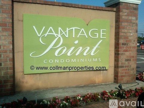 A sign for Vantage Point Condominiums is displayed in front of a brick wall.