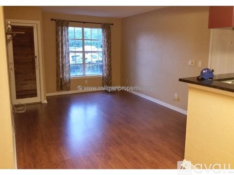 A room with wooden flooring and a window with curtains.