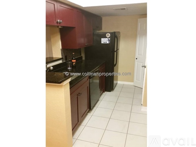 A kitchen with a black fridge and brown cabinets.