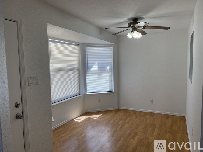 A room with a ceiling fan and wooden flooring.