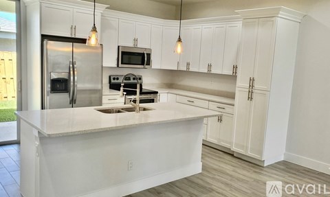 A kitchen with white cabinets and a white island.