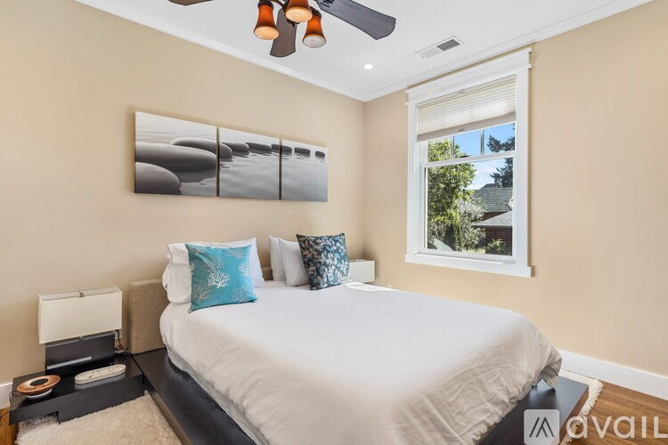 A bedroom with a bed, pillows, a ceiling fan, and a window.