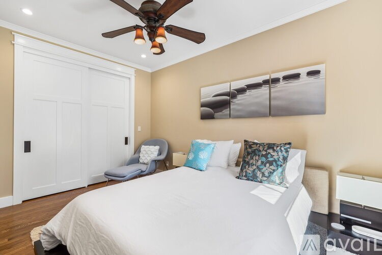 A bedroom with a bed, a chair, and a ceiling fan.