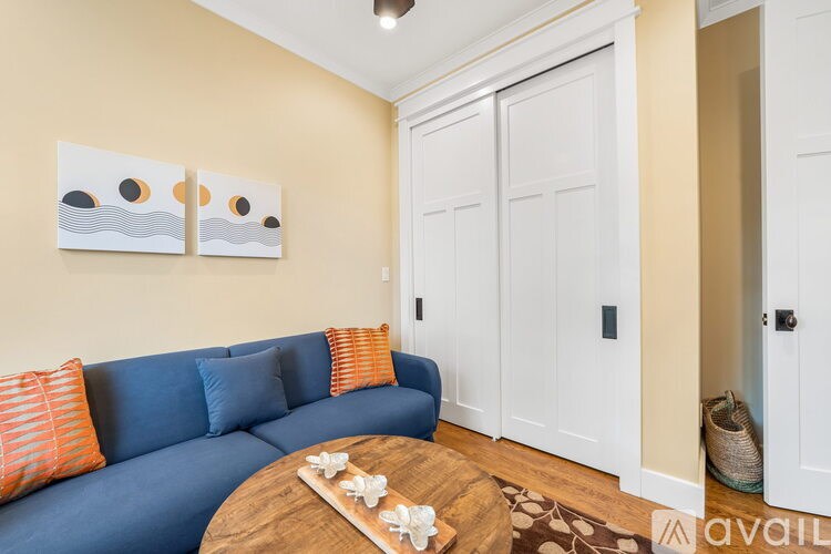 A living room with a blue couch and two orange pillows.