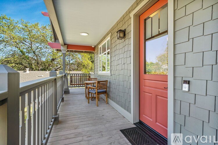A red door is on the right side of a porch.