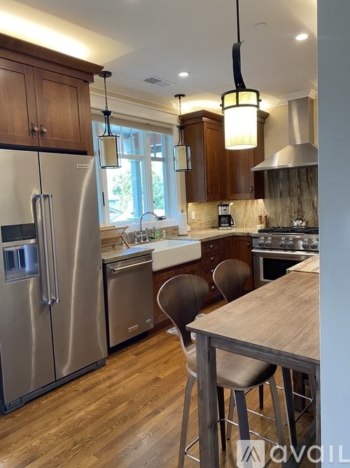 A kitchen with wooden cabinets and a stainless steel refrigerator.