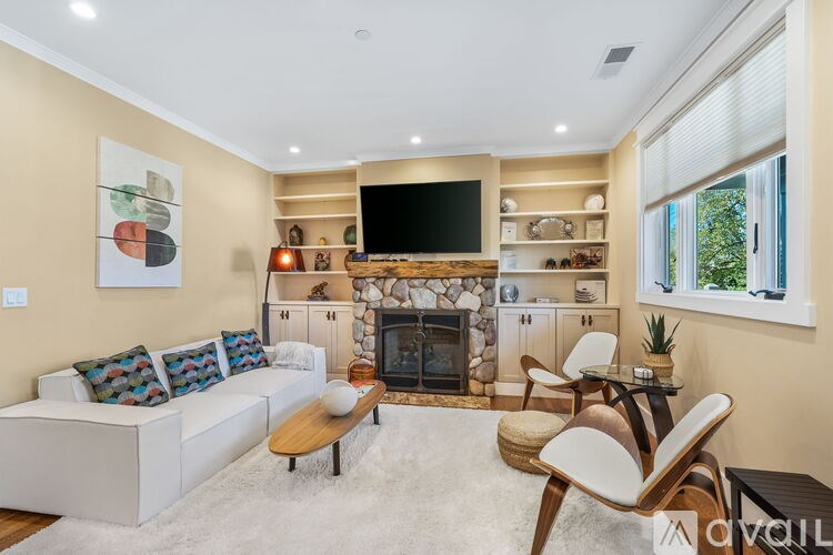 A living room with a white couch, a fireplace, and a TV mounted on the wall.