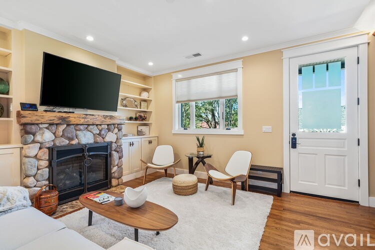 A living room with a stone fireplace and a flat screen TV mounted above it.