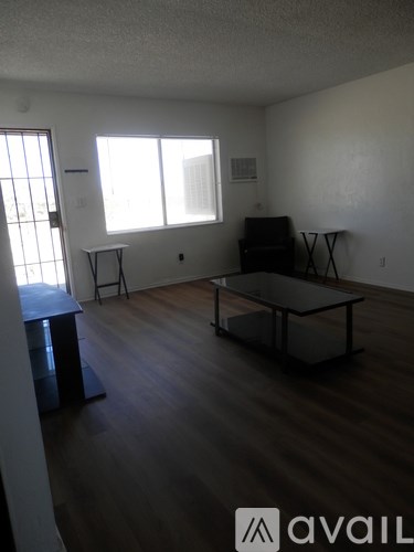 A living room with a black couch and a glass coffee table.