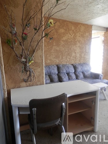 A room with a couch, a table, and a wall with a floral design.