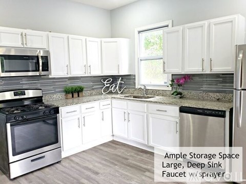 A kitchen with white cabinets and a large deep sink.