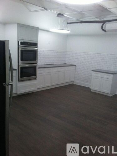 A kitchen with a black refrigerator and white cabinets.