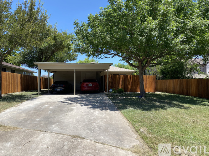 A carport with two cars parked underneath it.