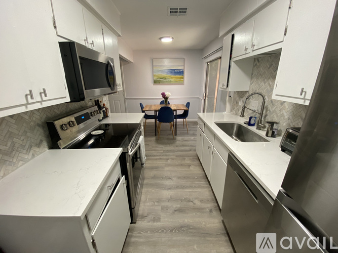A kitchen with white cabinets and a grey floor.