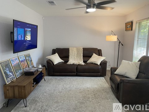 A living room with a brown couch and a flat screen TV mounted on the wall.