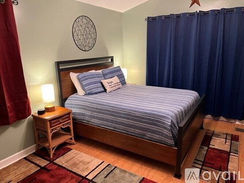 A bedroom with a bed, nightstand, and curtains.