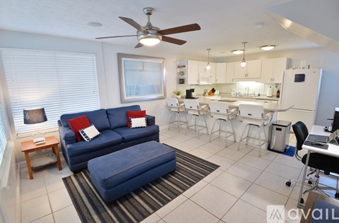 A living room with a blue couch and a kitchen in the background.