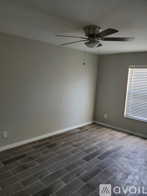 A room with a ceiling fan and a window with blinds.
