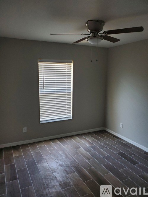 A room with a ceiling fan and a window with blinds.