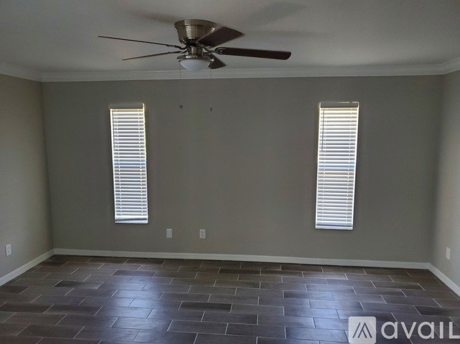 A room with a ceiling fan and two windows with blinds.