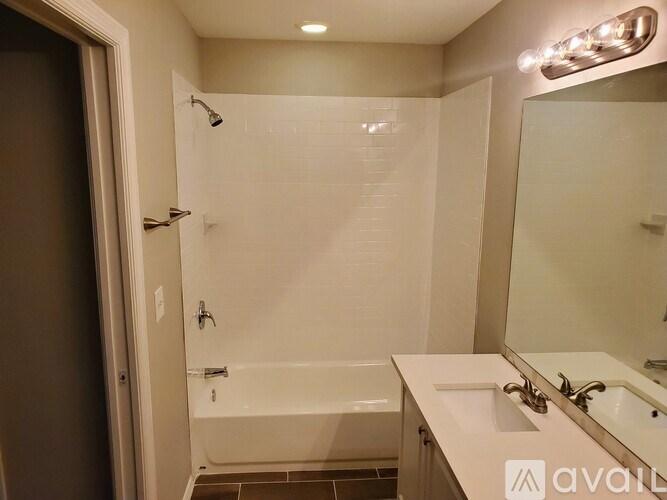 A bathroom with a white tub and sink, a mirror, and a shower.