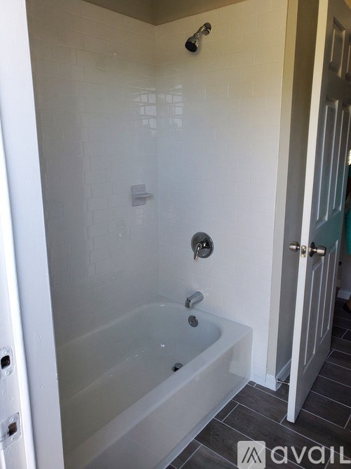 A bathroom with a glass shower stall and a white tub.