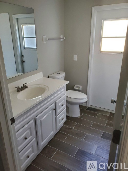 A bathroom with a toilet, sink, and mirror.