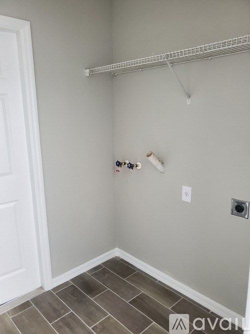 A white door is on the left side of a room with a white wall and a white shelf.